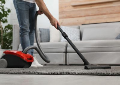 Young man using vacuum cleaner at home